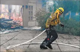  ?? Michael Owen Baker For The Times ?? A FIREFIGHTE­R runs back to his truck on Hitching Post Lane while battling the Woolsey fire on Friday in the upscale hillside neighborho­od of Bell Canyon.