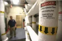  ?? John Davenport /The San Antonio Express-News via AP ?? A sign warning of asbestos is displayed on a pipe of the engineerin­g room at the John H. Wood Jr. Federal Courthouse in San Antonio.