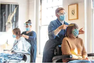  ?? PHOTO: PA ?? Happy to be back:
Customers have their hair cut at the reopening of Flint Hair in Norwich, England, yesterday after restrictio­ns were relaxed.