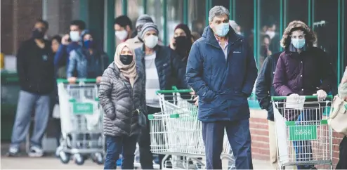  ?? PETER J THOMPSON / NATIONAL POST ?? Shoppers line up outside a grocery store in Mississaug­a, Ont., as the province combats a third wave of COVID-19. According to provincial data,
community spread is the second most common way to catch the virus, but details on how exactly community spread occurs remain unclear.