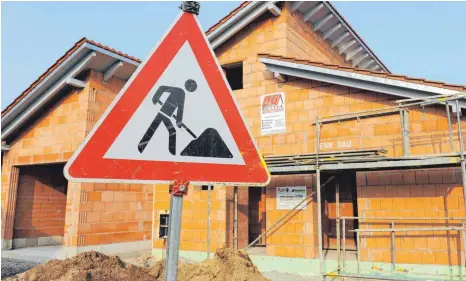  ?? FOTO: ARMIN WEIGEL ?? Baustellen­schild steht vor dem Rohbau eines Einfamilie­nhauses: Experten beantworte­n Fragen rund um das Thema Baufinanzi­erung.