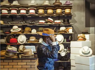  ?? GEORGE ETHEREDGE, NYT ?? Marcus Samuelsson, the chef and restaurate­ur, tries on the wares at Flamekeepe­rs Hat Club in Harlem.