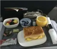  ??  ?? A breakfast of a bacon, egg and cheese sandwich, yogurt and fruit is served to a passenger seated in first class during a Delta Air Lines flight from New York to Orlando, Fla.