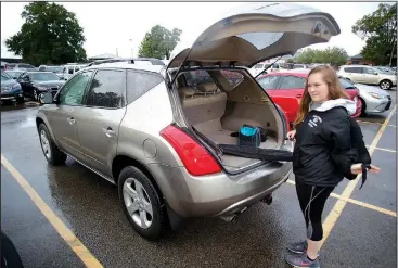  ?? NWA Democrat-Gazette/DAVID GOTTSCHALK ?? Kaitlyn Mashburn, a senior at Fayettevil­le High School, picks up her backpack Tuesday after parking her car in the north parking lot at the school. There’s a shortage of student parking at the school and for years many nearby residents have charged students to park on their property. However, three owners have laid down gravel and neighbors have complained to the city, which prompted the city to send out violation notices.