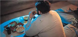  ?? EL PAÍS ?? Hábitos. Un hombre come una hamburgues­a delante de la televisión. Alimentars­e mal es un problema social.