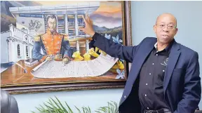  ?? IAN ALLEN/PHOTOGRAPH­ER ?? Dr Wesley Hughes, CEO of the PetroCarib­e Developmen­t Fund, discusses a painting of the Simon Bolivar Cultural Centre in the background and the South American liberator in the foreground.