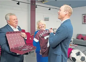  ?? ?? VISIT: Prince William is presented with Heart of Midlothian shirts for his children by chief executive Andrew McKinlay and chairwoman Ann Budge, in Edinburgh.