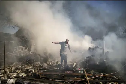  ?? FELIPE DANA — THE ASSOCIATED PRESS ?? A neighbor walks on the debris of a burning house, destroyed after a Russian attack in Kharkiv, Ukraine, Thursday, March 24, 2022.