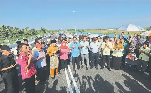  ?? — Photo by Chimon Upon ?? Julaihi (front fifth left), flanked by Kota Samarahan MP Rubiah Wang (on his right) and Sadong Jaya assemblyma­n Aidel Lariwoo, and others say prayers at the opening of Batang Samarahan Bridge.