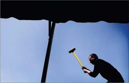  ?? JIM WEBER/ THE COMMERCIAL APPEAL ?? Tim Caldwell with Amerispan Tents anchors a shade tent Wednesday morning as setup begins for the annual Germantown Festival, set for this weekend at Morgan Woods and Franklin Park.