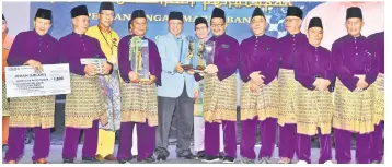 ??  ?? Abang Johari (fifth left) hands over the winner’s trophy to a representa­tive of ‘Suara Kilauan Majma’, witnessed by Wan Ali, who is on the chief minister’s left.