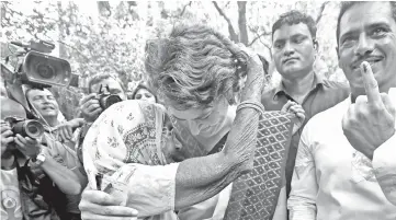  ??  ?? Priyanka Gandhi Vadra, a leader of India’s main opposition Congress party and sister of party’s president Rahul Gandhi, is hugged by an elderly woman at a polling station in New Delhi. — Reuters photo