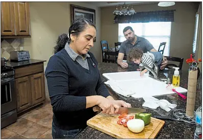  ?? NWA Democrat-Gazette/BEN GOFF ?? Maria Sanabria prepares a meal Thursday as her husband, Jose, plays with their daughter, Elena, in Centerton. Jose Sanabria said “it’s hard to really give an answer” when he was asked about his status as federal protection­s for Salvadoran­s are set to...