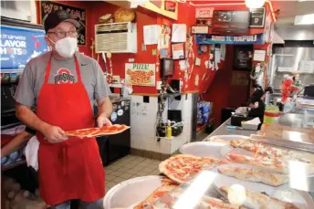  ?? — AFP photos ?? Esposito serves pizza at his restaurant Gianni’s Pizza in Wilmington, Delaware.