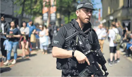  ?? Picture: Jeff J Mitchell. ?? Armed police patrol as members of the public queue to lay flowers in St Ann’s Square.