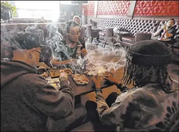  ?? Jeff Chiu The Associated Press ?? Rick Thompson, clockwise from left, Keith Baskervill­e and Xavier Baskervill­e smoke marijuana at Barbary Coast Dispensary in San Francisco in 2018.