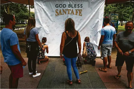  ?? Michael Ciaglo photos / Houston Chronicle ?? People write words of hope and encouragem­ent for victims of the Santa Fe High School mass shooting on a banner at Discovery Green Park.