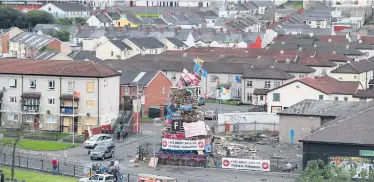  ??  ?? Masked youths (also right) on top of a controvers­ial bonfire in the Bogside estate in Derry