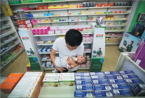  ?? CHEN WEI / FOR CHINA DAILY ?? A man buys medicine for his sick child at a drugstore in Yuncheng, Shanxi province. Many parents treat their children’s minor ailments themselves.