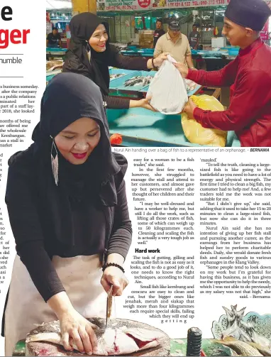  ??  ?? Nurul Ain handing over a bag of fish to a representa­tive of an orphanage. – BERNAMA