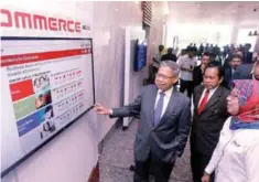  ??  ?? Mustapa (left) looking at an exhibit on e-commerce at Miti. Accompany him are Deputy Internatio­nal Trade and Industry Minister Datuk Ahmad Maslan and SME Corp CEO Datuk Dr Hafsah Hashim.