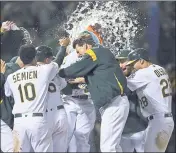  ?? BEN MARGOT — THE ASSOCIATED PRESS ?? A’s slugger Khris Davis is mobbed by his teammates after hitting the game-winning home run Saturday.