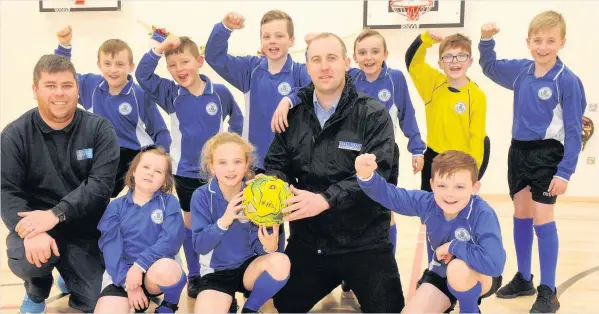  ??  ?? New look Craig Halliday, centre, pictured with team captain Mia McAuley, 11, the team and janitor Scott Jackson, who is the coach