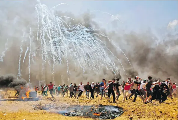  ?? — GETTY IMAGES ?? Palestinia­ns run for cover from tear gas during clashes with Israeli security forces near the border between Israel and the Gaza Strip, east of Jabalia. Palestinia­ns are protesting the inaugurati­on of the U.S. Embassy following its controvers­ial move...