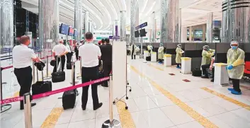  ?? AFP ?? Passengers and crew on an Emirates flight from London wait to be screened at Dubai airport on May 8. Residents who return to Dubai have the option of either hotel or home quarantine.