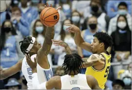  ?? GERRY BROOME — THE ASSOCIATED PRESS ?? Michigan guard Eli Brooks (55) passes while North Carolina forward Armando Bacot (5) and guard Caleb Love defend during the game in Chapel Hill, N.C., on Wednesday.