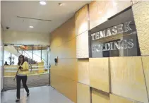  ??  ?? AN EMPLOYEE of the Temasek Holding walks past a company sign in Singapore on July 8, 2010.