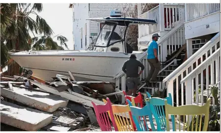 ?? AFP ?? Picking up the pieces: A man and his nephew recovering items from his home after it was damaged by Hurricane Michael in Mexico Beach, Florida. —