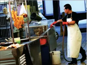  ?? EDMOND TANG / CHINA DAILY ?? A live poultry vendor washes chicken cages at the Kowloon City Market on Tuesday, after Hong Kong confirmed its first human case of the deadly H7N9 bird flu on Monday.