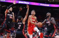  ?? KEVIN C. COX
Getty Images North America ?? Trae Young of the Atlanta Hawks elevates for a layup against three Miami Heat defenders during Game 3 at State Farm Arena in Atlanta on Friday night.