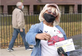  ?? AP FILE PHOTO ?? Trinity Dishmon takes a picture of her mail-in ballot before dropping it off at an early voting polling site at the Dr. Martin Luther King Jr. Center in Chicago last month.