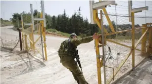  ?? (Ronen Zvulun/Reuters) ?? A SOLDIER OPENS a gate to an area near Shlomi where the army is creating an additional barrier on the Lebanese border.