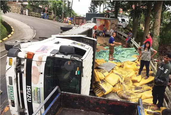  ?? PAUL JUN E. ROSAROSO ?? A delivery truck falls on its side after colliding with the delivery van of Julies Bakeshop in Barangay Malubog, Cebu City yesterday. At least one person was killed in the accident.