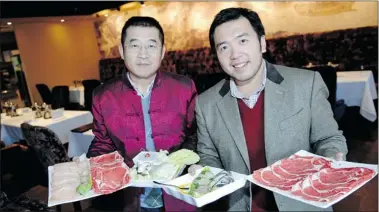  ?? TROY Fleece/leader-post photos ?? Co-owners Daway Yang, left, and Jason Zhao hold up a few dishes at the Simmer Hot Pot Restaurant on Wednesday.