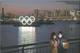  ?? (File Photo/AP/Jae C. Hong) ?? Two women take a selfie March 12, 2020, with the Olympic rings in the background in the Odaiba section of Tokyo. Tokyo Governor Yuriko Koike spoke after the World Health Organizati­on labeled the spreading virus a “pandemic,” a decision almost certain to affect the Tokyo Olympics.