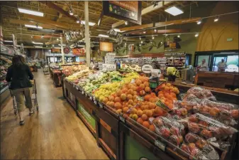  ?? CHRIS DILLMANN — THE ASSOCIATED PRESS FILE ?? Shoppers make their way around the produce section at City Market in Eagle, Colo., in May 2017.