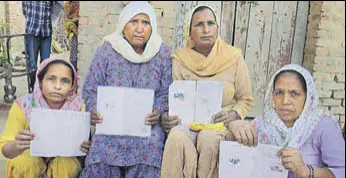  ?? SANJEEV KUMAR/HT ?? Women enrolled under MGNREGS showing their job cards at Lakhi Jungle village in Bathinda district on Friday. They said they have not been paid their wages for months.