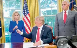  ?? — AP ?? US President Donald Trump gives the pen he used to sign the executive order to end family separation­s at the border to homeland security secretary Kirstjen Nielsen ( left) as vice- president Mike Pence watches in the Oval Office.