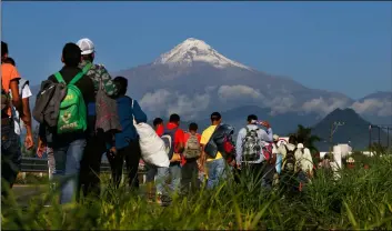  ?? AP PhoTo/MArco UgArTe ?? Central American migrants begin their morning trek as part of a thousands-strong caravan hoping to reach the U.S. border, as they face the Pico de Orizaba volcano upon departure from Cordoba, Veracruz state, Mexico, on Monday.