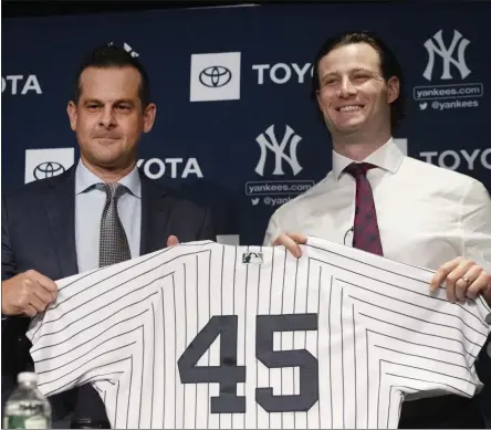  ?? MARK LENNIHAN - THE ASSOCIATED PRESS ?? New York Yankees manager Aaron Boone, left, and pitcher Gerrit Cole hold up a jersey as Cole is introduced as the baseball club’s newest player during a media availabili­ty, Wednesday, Dec. 18, 2019 in New York. The pitcher agreed to a 9-year, $324 million contract.