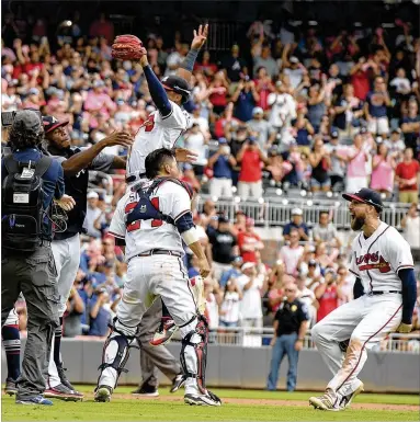  ?? BRANT SANDERLIN / BSANDERLIN@AJC.COM ?? The Braves celebrate after clinching the National League East crown against the Philadelph­ia Phillies at SunTrust Park on Saturday. “I’m thinking, ‘It’s really true. We really did it,’ ” says manager Brian Snitker.