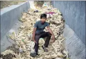  ??  ?? Brijesh, who claims to be 16 years old but does not know his birthday, sits on corn stalks in Noida, India. Children sell corn along this busy expressway on the outskirts of New Delhi. They spend their days trying to flag down drivers.