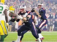  ?? STEVEN SENNE/ASSOCIATED PRESS ?? New England quarterbac­k Tom Brady, right, looks for a receiver under pressure from Green Bay. Brady threw for 294 yards and one touchdown on Sunday night.