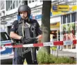  ?? FOTO: DPA ?? Ein schwerbewa­ffneter Polizist vor dem Tatort in Barmbek.