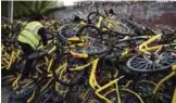  ??  ?? A worker climbs onto a pile of Ofo shared bicycles at a repair center in Beijing.