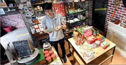  ?? LIN SHANCHUAN / XINHUA ?? A man from Taiwan stands in a souvenir shop he owns in Pingtan, Fujian province.